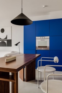A modern blue kitchen featuring a wooden dining table and chairs.