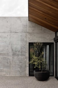 A modern entrance featuring a concrete wall and a black glass door.