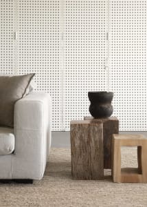 A rustic industrial living room featuring a white couch, wooden stools, and a textured rug.
