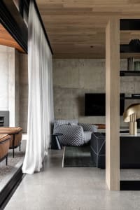 A modern industrial living room with a concrete accent wall, minimalist furniture, and sleek design elements.
