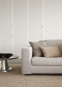 A modern living room featuring a beige fabric sofa with grey and beige cushions, a metal coffee table with a black bowl, and 