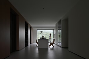 Minimalist living room with wood furniture and a large window overlooking nature.