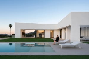 Modern minimalist home exterior with white concrete exterior walls and a large swimming pool.