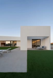 Modern minimalist residential exterior with concrete, glass, and steel materials.
