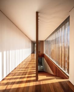 A modern minimalist corridor with wooden flooring and a large window.