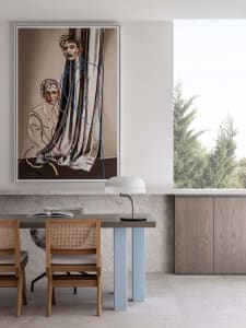 Modern dining room with wooden chairs and a marble table, featuring a fabric curtain and abstract artwork.