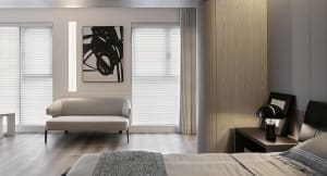 A modern living room featuring a white couch and a minimalist art piece on the wall.