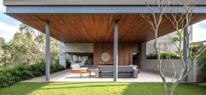 Modern living space with wooden ceiling, gray sofa, and outdoor seating area