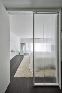 A modern bedroom featuring a glass sliding door.