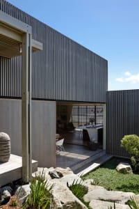A modern house exterior with a metal-clad facade on a clear day with blue sky.