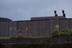 Modern residential exterior with metal cladding and illuminated windows.