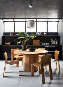 Minimalist kitchen with wooden table, concrete floor, and glass pendant light.