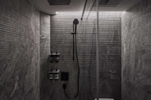 A modern minimalist bathroom with marble tiles, a glass shower enclosure, and sleek black fixtures.