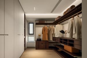 A modern closet with wooden shelves, hanging clothes, and a window.
