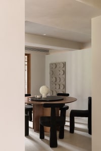 A modern interior design with a wooden dining table and black chairs.