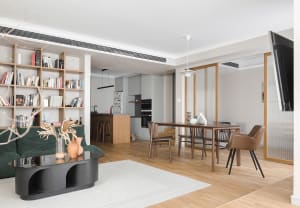 Modern living room with wood flooring, minimalistic furniture, and a large bookshelf.