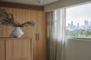A modern residential interior featuring wooden cabinets and glass curtains.