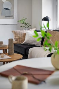 A modern living room featuring textiles, wood, and indoor plants.