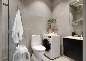 Modern minimalist bathroom with concrete walls, white toilet, white washing machine, black sink cabinet, and white towels.
