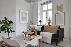 A modern living room with a black sofa, white armchairs, and minimalist decor.