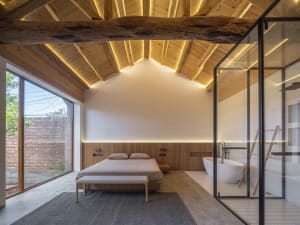 Modern minimalist bedroom featuring wooden elements and a white bathtub.