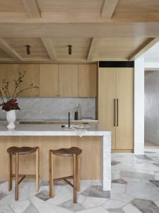 A modern kitchen featuring marble countertops and wooden cabinets.