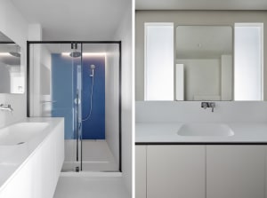 Minimalist bathroom with white and gray color scheme and glass shower enclosure.