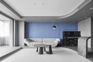 Modern living room with white furniture, blue accent wall, and black and white coffee tables.