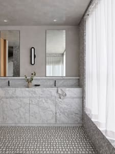 Modern bathroom featuring marble countertops and floors with a white curtain on the right side.