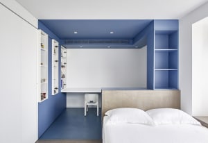 A minimalist bedroom with blue and white color scheme and a built-in desk.