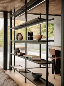 A modern living room featuring metal and wood shelving units with various decorative items and books.