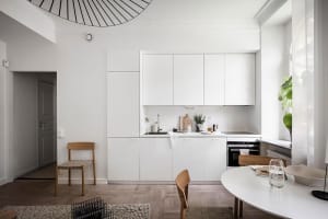 A modern minimalist kitchen featuring white cabinetry and a sleek, contemporary design.