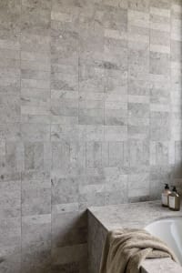 Modern minimalist bathroom with stone tile walls and a clean, uncluttered design.