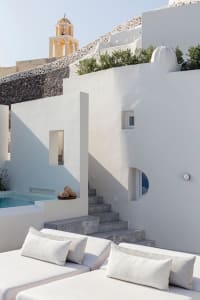 A minimalist residential patio with white plaster walls, stone steps, and a small pool.