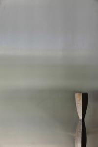 A minimalist metal sculpture against a grey gradient background.