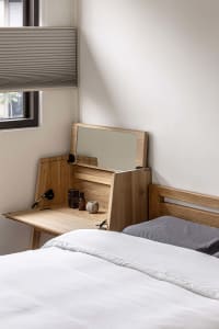 Minimalist bedroom with wooden headboard and wooden desk.