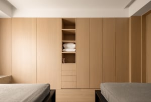 A modern minimalist bedroom with wooden paneling, featuring two beds and a built-in wardrobe.
