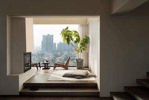 A minimalist living room with a modern design featuring wood furniture, concrete flooring, and large windows.