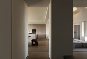A modern minimalist kitchen featuring light-colored wooden cabinets and a wooden dining table.