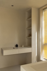 A minimalist white interior with a floating desk and shelves.