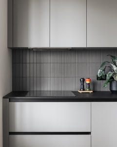 A minimalist kitchen with gray tiles on the backsplash and cabinets.