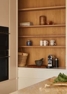 A minimalist kitchen with wooden shelves holding books, mugs, and a coffee machine. Interior design focus on storage solution