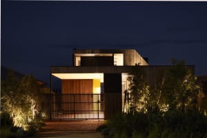A modern residential house at night with warm interior lights and external lighting features.