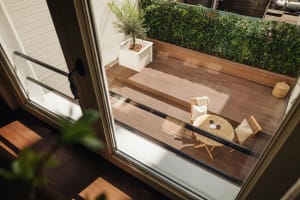 Modern porch features a wooden table with chairs and a potted plant.