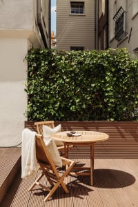 A cozy outdoor space featuring wooden furniture and greenery.