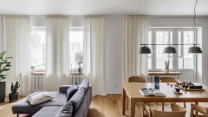 A modern minimalist living room with neutral colors, large windows, and a wooden floor.