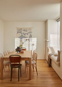 A minimalist dining room featuring a wooden table and chairs.