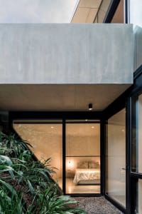 A modern concrete bedroom featuring a cozy bed with a floral pattern on the mattress and pillows.