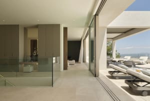 Contemporary living space with glass walls and modern furniture, featuring a comfortable lounge area and a stunning outdoor t