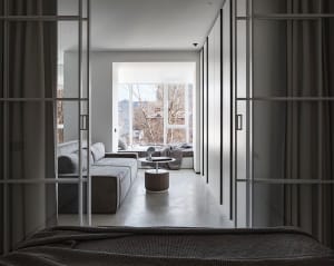 A modern living room featuring a concrete sectional sofa and a circular ottoman with a book on top.